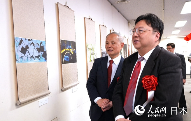 主辦方代表馮學敏（左）向陳巍總領事（右）介紹展出作品。人民網 許可攝