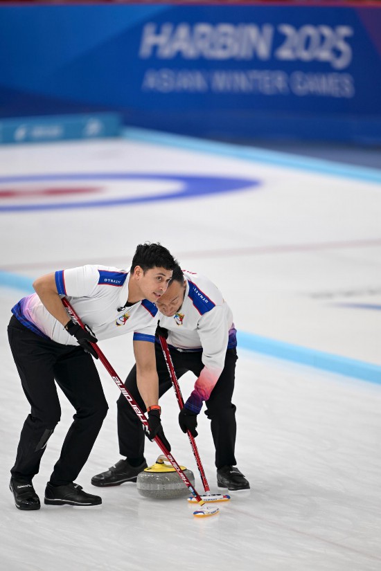 2月13日，菲律賓隊選手恩里克·加布里埃爾·普菲斯特（左）和阿蘭·比特·弗雷在比賽中擦冰。新華社記者 黃博涵 攝