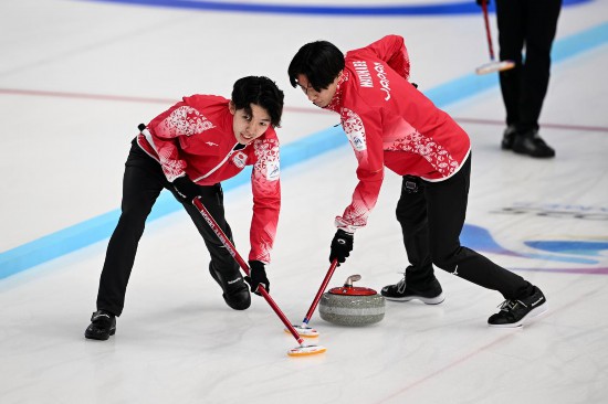 2月13日，日本隊選手宮櫻介（左）和渡邊陽紀在比賽中擦冰。新華社記者 黃博涵 攝