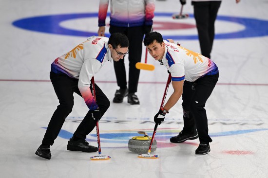 2月13日，菲律賓隊選手恩里克·加布里埃爾·普菲斯特（右）和克里斯蒂安·帕特里克·哈勒在比賽中擦冰。新華社記者 黃博涵 攝